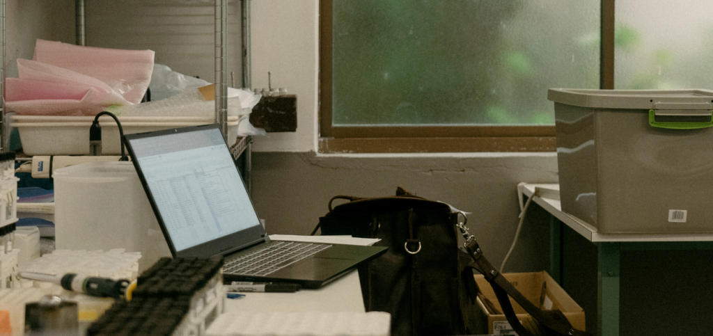 Laptop on cluttered desk near window in a workspace or laboratory setting